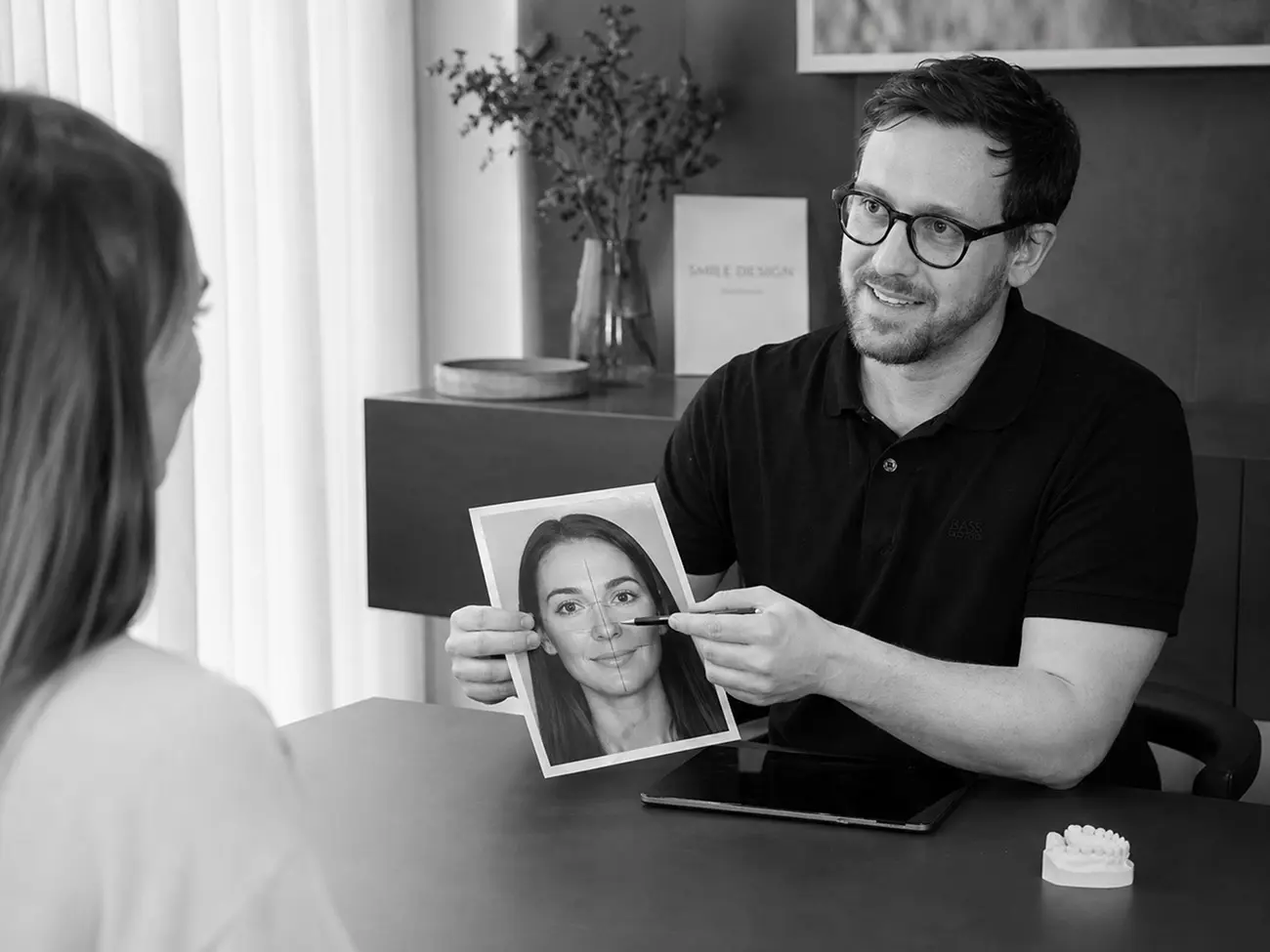 Beratungsgespräch zum Thema Veneers zwischen Zahnarzt und Patientin in der Praxis zhochdrei